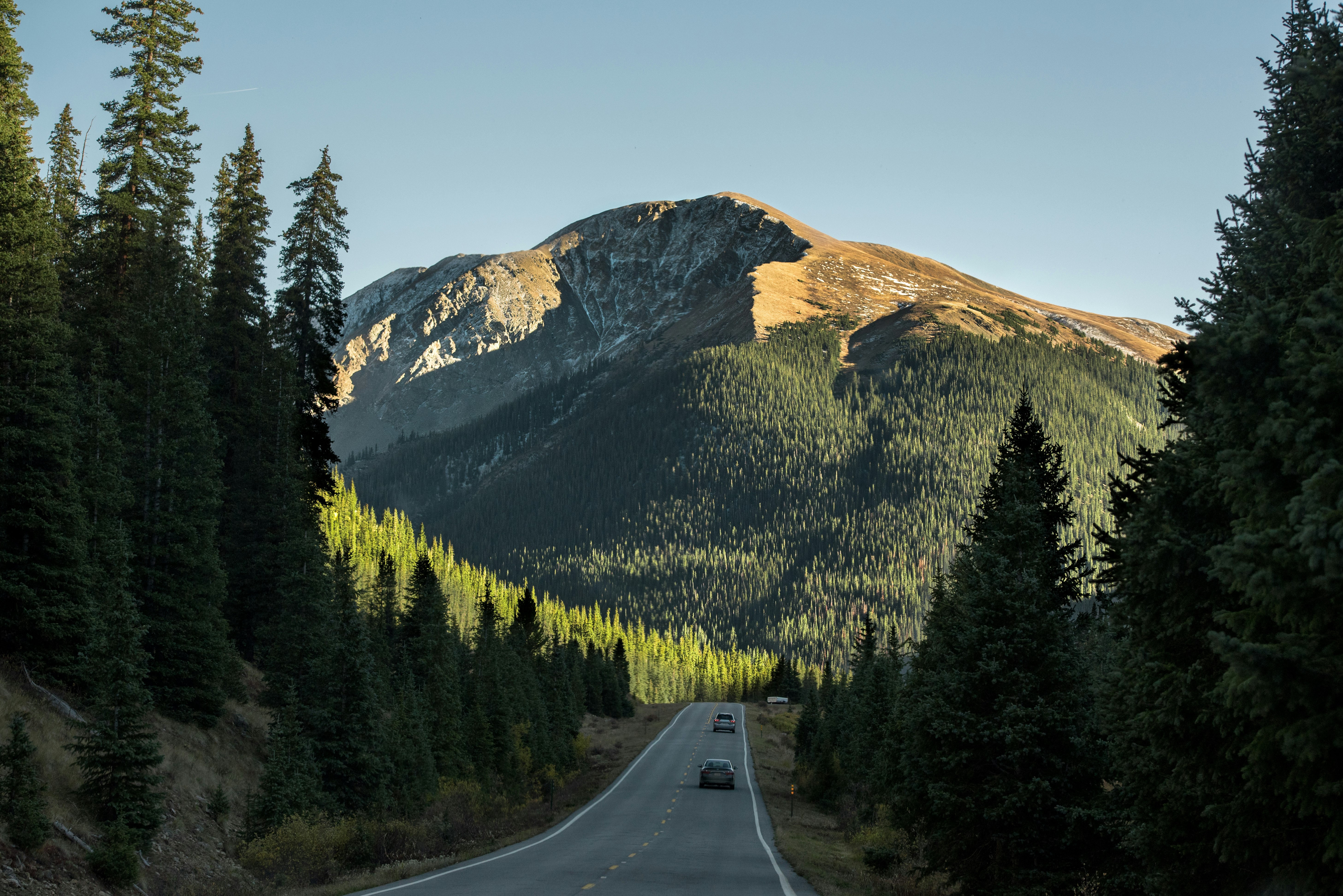 two vehicle on gray concrete pavement towards mountain taken at daytime